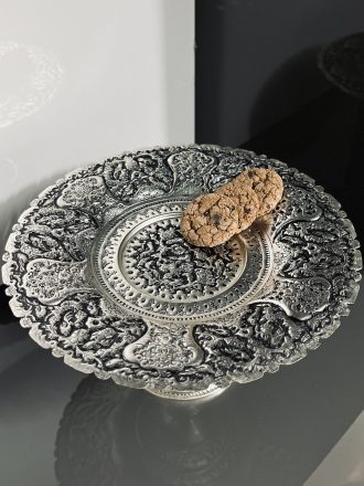شیرینی‌خوری سایز ۳۰ با نقش گل و مرغ ممتاز، آبکاری نقره و تکنیک سیاه قلم، یکی از فاخرترین ظروف پذیرایی در سبک سنتی ایرانی است. این اثر هنری با فرم کلاسیک و ابعاد مناسب، انتخابی ایده‌آل برای پذیرایی از مهمانان در مناسبت‌های خاص، به‌ویژه با شیرینی‌های سنتی اصفهان است.