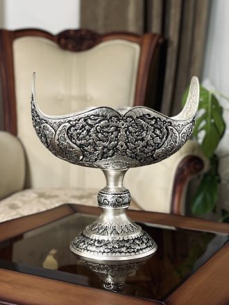 کشکول مسی سایز ۳ با نقش گل و مرغ ممتاز، اثری فاخر از هنر قلمزنی اصفهان است که با آبکاری نقره و تکنیک سیاه قلم، جلوه‌ای سلطنتی و هنری به فضای پذیرایی یا دکوراسیون شما می‌بخشد.