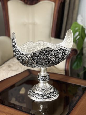 کشکول مسی سایز ۳ با نقش گل و مرغ ممتاز، اثری فاخر از هنر قلمزنی اصفهان است که با آبکاری نقره و تکنیک سیاه قلم، جلوه‌ای سلطنتی و هنری به فضای پذیرایی یا دکوراسیون شما می‌بخشد.