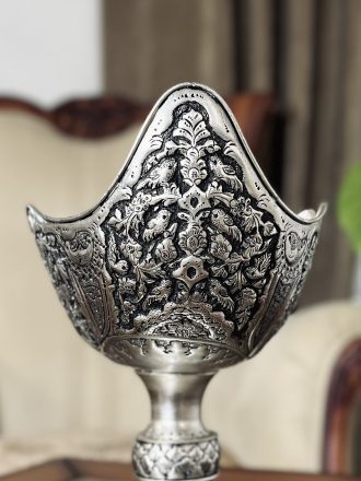 کشکول مسی سایز ۳ با نقش گل و مرغ ممتاز، اثری فاخر از هنر قلمزنی اصفهان است که با آبکاری نقره و تکنیک سیاه قلم، جلوه‌ای سلطنتی و هنری به فضای پذیرایی یا دکوراسیون شما می‌بخشد.