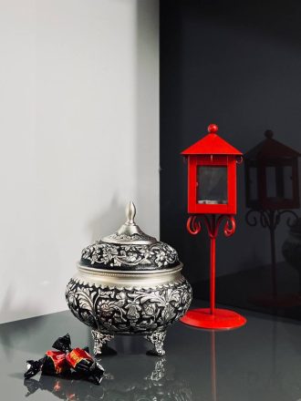 شکلات‌خوری ۴ پایه قلمزنی گل شیرازی (گل ترکی) این شکلات‌خوری فاخر با طراحی گل شیرازی (گل ترکی) و اجرای هنرمندانه‌ی قلمزنی سیاه‌قلم بر روی سطحی با آبکاری نقره، جلوه‌ای درخشان و ماندگار از صنایع دستی ایران است.