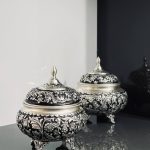 شکلات‌خوری ۴ پایه قلمزنی گل شیرازی (گل ترکی) این شکلات‌خوری فاخر با طراحی گل شیرازی (گل ترکی) و اجرای هنرمندانه‌ی قلمزنی سیاه‌قلم بر روی سطحی با آبکاری نقره، جلوه‌ای درخشان و ماندگار از صنایع دستی ایران است.