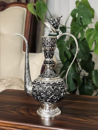 آفتابه و لگن قلمزنی گل شیرازی (گل ترکی) | آبکاری نقره سیاه‌قلم این آفتابه و لگن فاخر با نقش اصیل گل شیرازی (گل ترکی) و اجرای هنرمندانه‌ی قلمزنی سیاه‌قلم بر روی سطحی با آبکاری نقره، نمونه‌ای درخشان از صنایع دستی ایران است.