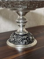 شیرینی‌خوری قلمزنی گل شیرازی (گل ترکی) | آبکاری نقره سیاه‌قلم این شیرینی‌خوری فاخر با نقش اصیل گل شیرازی (گل ترکی) و اجرای هنرمندانه‌ی قلمزنی سیاه‌قلم بر روی سطحی با آبکاری نقره، جلوه‌ای درخشان و ماندگار از صنایع دستی ایران است.