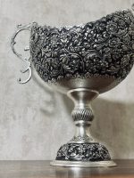 کشکول قلمزنی گل شیرازی (گل ترکی) | آبکاری نقره سیاه‌قلم این کشکول فاخر با نقش اصیل گل شیرازی (گل ترکی) و اجرای هنرمندانه‌ی قلمزنی سیاه‌قلم بر سطحی با آبکاری نقره، نمونه‌ای درخشان از صنایع دستی اصفهان است.
